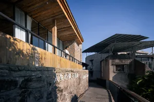 A modern residential loft with wooden floors, stone walls, and a metal roofing structure.