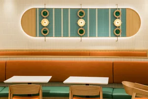 A modern restaurant interior with circular porthole windows and upholstered seating.