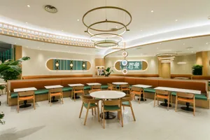 Modern restaurant interior featuring orange fabric seating and wooden furniture.