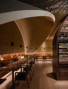 Modern restaurant interior featuring wooden tables, leather seating, and metal accents