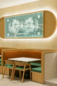 Modern restaurant interior with wooden furniture, seating arrangements, and a glass wall displaying the restaurant's name and