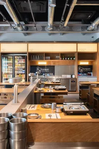 An interior view of a modern restaurant kitchen with wooden elements and stainless steel appliances.