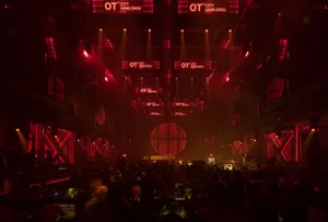 A nightclub interior with red lighting and people dancing on a dance floor.