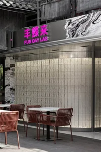 Outdoor seating area of a restaurant with marble accents and concrete walls.