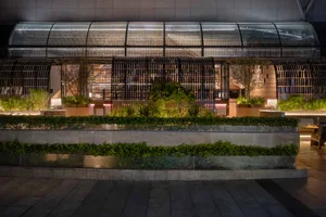 Modern industrial restaurant exterior with metal, glass, concrete, and greenery