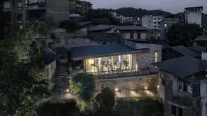 A modern storefront with a glass door illuminated at night, surrounded by buildings and trees.