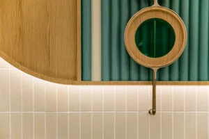 A close-up view of a round window with green curtains and wooden details in an interior design setting.