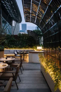 A modern restaurant with metal structures and greenery outdoors.
