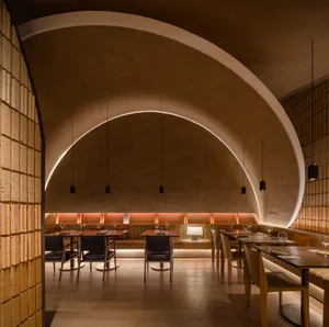 A modern restaurant interior with a warm material palette.