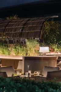 Modern, industrial rooftop bar with metallic structures, glass elements, and concrete flooring.