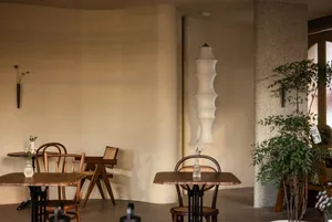 A cozy cafe interior with tables, chairs, and hanging lamp in a minimalist design.
