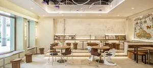 A casual café interior with wood tables, metal stools, and plaster walls.