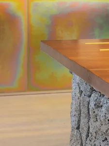 A close-up of a modern concrete table with a metallic top, featuring a rock column base.