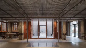 Industrial-style coffee shop with brick walls, concrete flooring, metal columns, wooden furniture, and brick columns.
