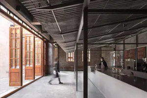 Industrial-style coffee shop with concrete and brick accents, featuring a sleek coffee bar counter.