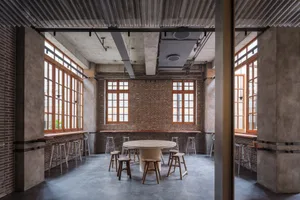 Industrial design restaurant interior with brick walls, concrete flooring, and large windows.