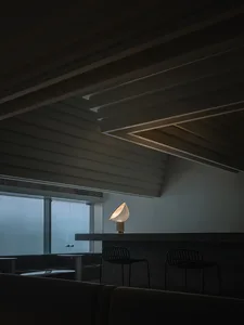 Minimalist design of a bar interior with concrete materials and a single light fixture.