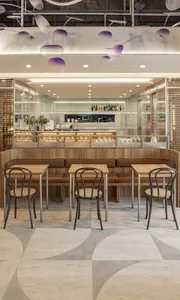 A modern cafe interior with wooden tables and chairs, minimalist decor, and a contemporary bar counter.