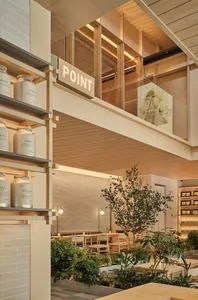 Contemporary cafe interior with wooden elements, glass partitions, and green plants.