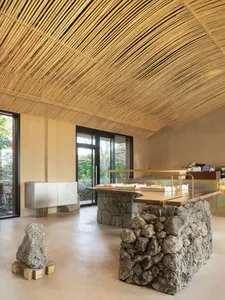 A modern cafe with stone and concrete interior, showcasing wooden tables and seating.