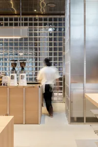 A modern coffee shop interior featuring glass block tiles on the wall.