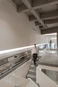A modern interior with concrete walls and floor, featuring a minimalist aesthetic and exposed concrete ceiling beams.
