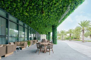 An outdoor lounge area with greenery-covered ceiling and glass walls