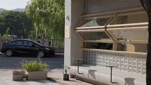 A modern storefront with a glass window and greenery.