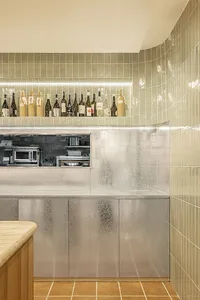 Modern kitchen interior with glass tiles on the wall and a concrete counter.