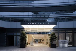 A modern, minimalist office entryway with a glass front and concrete materials.