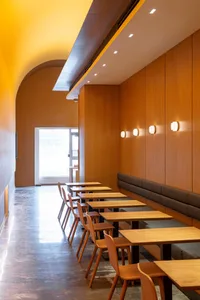 A modern restaurant interior with wooden tables, chairs, and walls.