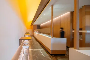 A sleek, modern restaurant interior with a wood and steel counter illuminated by soft lighting.