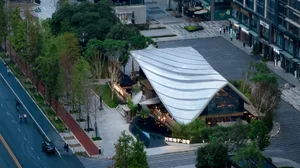 A modern shopping center with a metal roof and greenery.
