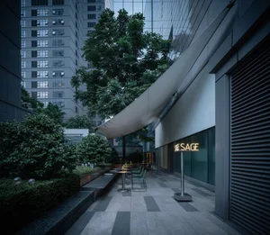 Outdoor cafe with glass seating area, concrete pavement, and surrounding trees.