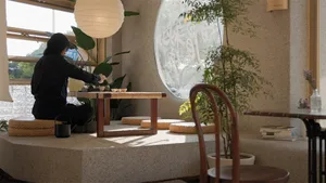 A person sitting at a wooden table in a cafe with concrete surroundings.