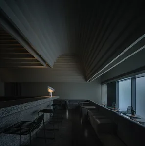 Modern cafeteria with concrete and metal interiors, featuring seating areas and lighting fixtures.