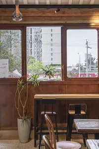 A cozy cafe interior featuring wooden furniture and a window view of urban buildings.