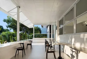 Modern cafeteria interior featuring sleek white surfaces, glass walls, and large windows.