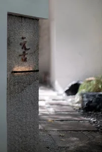 A minimalist entrance sign made of granite with Japanese characters etched into it.