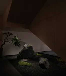 A minimalist interior featuring concrete rocks and moss.