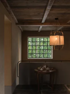 A minimalist interior design featuring a wooden window, table, and chandelier with a warm, soft light.