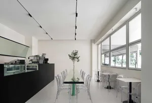 Modern cafe interior with glass tables, metal chairs, and minimalist design.