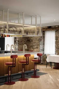 A modern restaurant bar featuring wood, glass, and stone materials with stylish red bar stools.