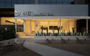 A modern restaurant exterior with concrete walls and a warm, inviting entrance.