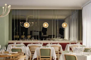 Modern restaurant interior with white tables, chairs, and pendant lights.