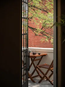 A wooden balcony terrace with a small table, chair, and teapot.