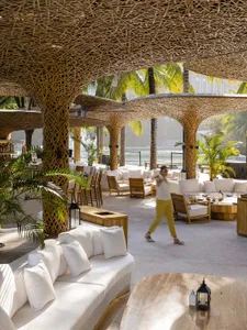 A modern cafeteria interior featuring natural fibers in the design, with white seating areas and white table lanterns.