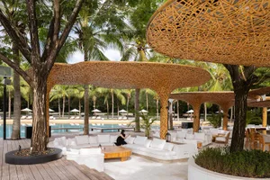 A modern poolside bar featuring woven stick architectural structures.