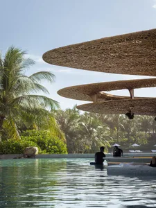 A poolside lounge area featuring bamboo structures with a modern design