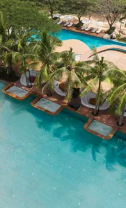 Aerial view of a resort poolside area with concrete structures and palm trees.